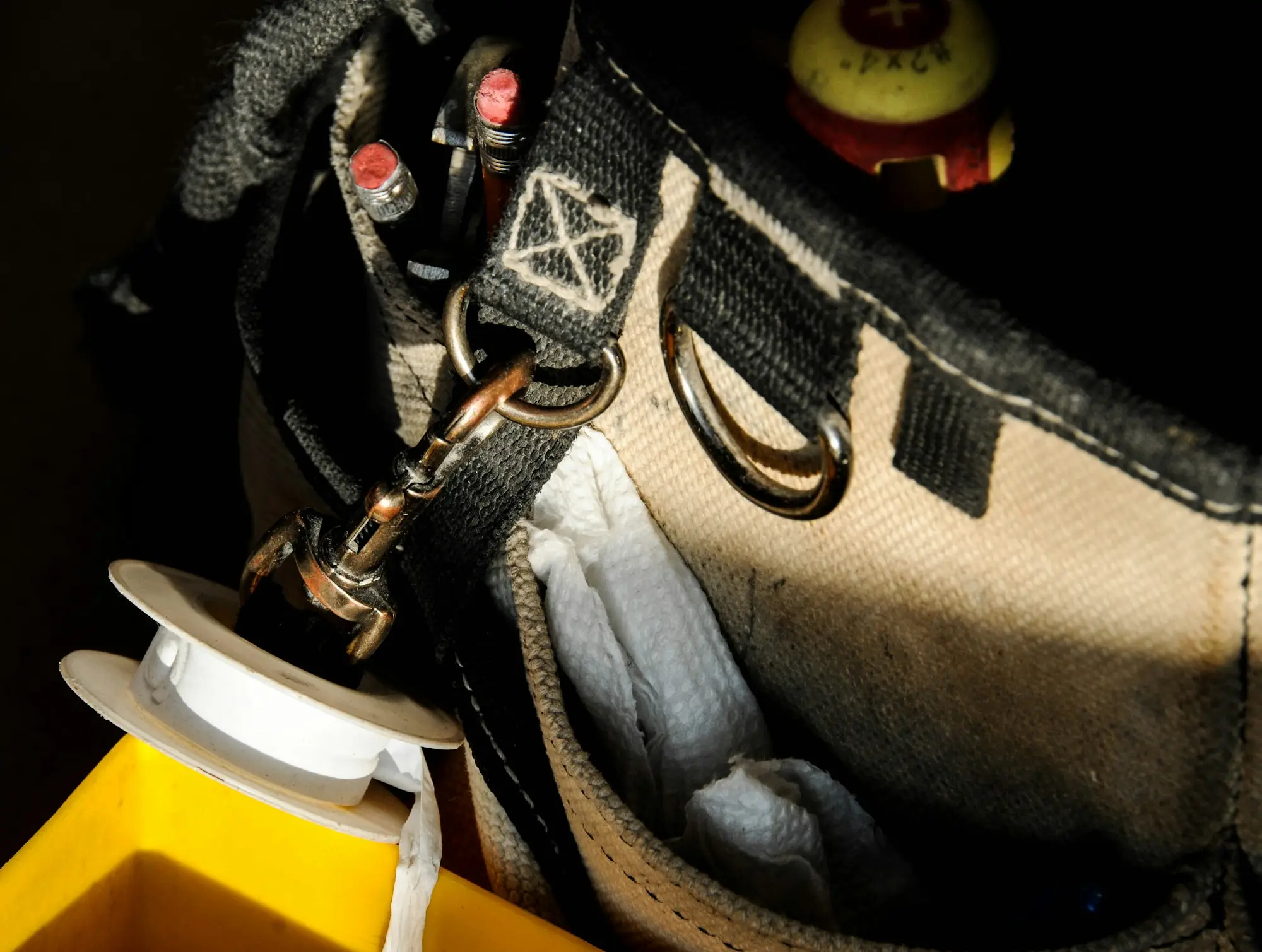 A tradie's canvas tool bag with pliers, screwdrivers and rags, the kind of kit that rides in a work ute every day